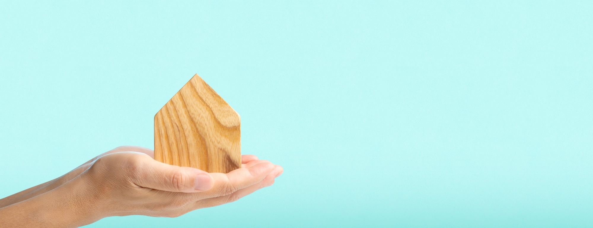 hand holding home wood at blue background.real estate concept