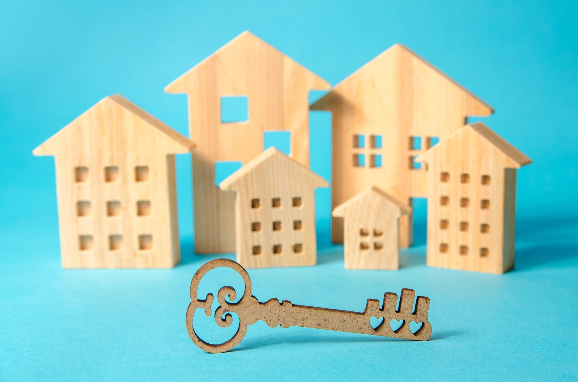 Key on the background of miniature wooden houses. Real estate buying and selling concept.